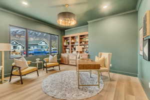 Sitting room featuring light wood-style flooring, a desk, crown molding, and recessed lighting