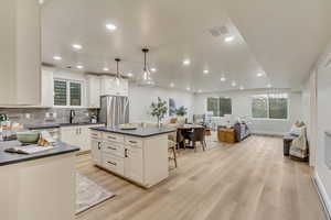 Kitchen featuring decorative backsplash, open floor plan, pendant lighting, dark countertops, and recessed lighting