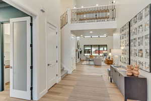 Hallway with recessed lighting, a towering ceiling, light wood finished floors, and stairway