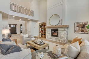 Living area with wood finished floors, a fireplace, a high ceiling, and recessed lighting