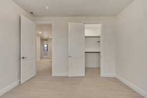 Unfurnished bedroom featuring light colored carpet and a walk in closet