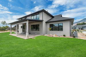 Back of house with a lawn, a patio area, stucco siding, and a mountain view