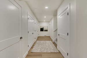 Hallway featuring light wood-type flooring, recessed lighting, and stairs