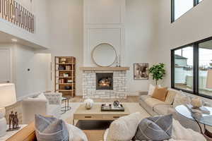Living area with a towering ceiling, wood finished floors, and a fireplace