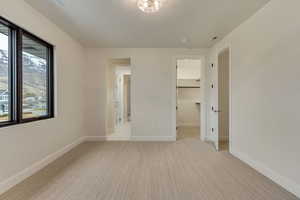 Unfurnished bedroom with light colored carpet and a spacious closet