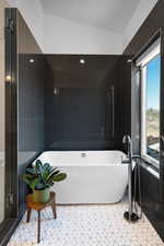 Bathroom with a soaking tub, tile patterned flooring, and tile walls