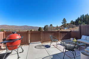Fenced backyard featuring grilling area, a mountain view, a patio, a gate, and outdoor lounge area