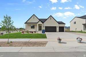 View of front of house featuring driveway, stucco siding, a front yard, a porch, and an attached garage