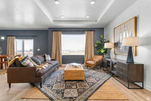 Living area featuring a tray ceiling, light wood-style floors, and recessed lighting