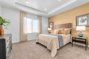 Bedroom featuring a raised ceiling, light carpet, and recessed lighting
