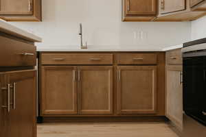 Kitchen with light wood-style flooring, brown cabinets, and light countertops