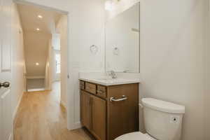 Half bath featuring vanity, light wood finished floors, and recessed lighting