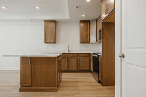 Kitchen featuring brown cabinetry, recessed lighting, light countertops, light wood-type flooring, and stainless steel electric range