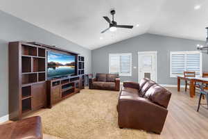 Living area with vaulted ceiling, light wood finished floors, a chandelier, a ceiling fan, and recessed lighting