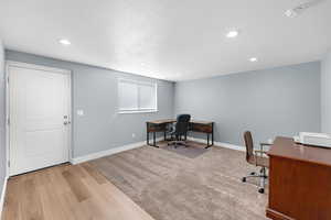 Office space with a textured ceiling, light wood finished floors, and recessed lighting