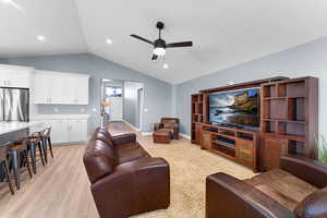 Living room with light wood finished floors, lofted ceiling, a ceiling fan, and recessed lighting