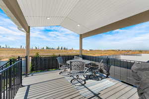 Wooden terrace with outdoor dining area, a view of countryside, and grilling area
