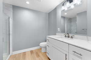 Full bathroom with vanity, light wood-style floors, a marble finish shower, and recessed lighting