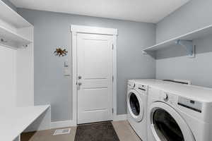 Laundry area with light tile patterned flooring and washing machine and clothes dryer