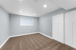 Unfurnished bedroom featuring dark carpet, recessed lighting, and a closet