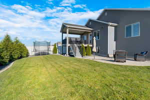 Back of property with stairway, a trampoline, a patio area, and stucco siding