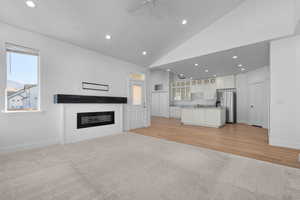 Kitchen featuring open floor plan, white cabinets, recessed lighting, glass insert cabinets, and a glass covered fireplace. New carpet coming soon.