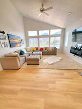 Living area with wood finished floors, high vaulted ceiling, and a ceiling fan
