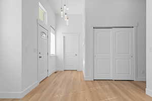 Foyer entrance featuring light wood-style flooring and a high ceiling. closet and study/bed doors shown
