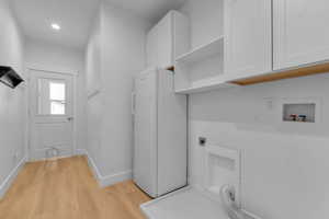 Laundry area with light wood-type flooring, hookup for an electric dryer, cabinet space, washer hookup, and recessed lighting. Pet door for cat room or storage