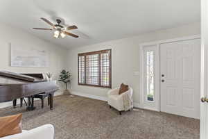 Foyer with lofted ceiling, carpet floors, and a ceiling fan