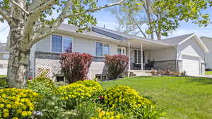 Ranch-style home featuring a front lawn, brick siding, covered porch, and a garage