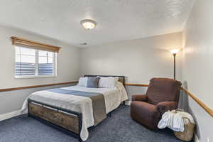 Carpeted bedroom featuring a textured ceiling and baseboards