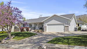 Ranch-style house with a porch, concrete driveway, a front yard, an attached garage, and brick siding