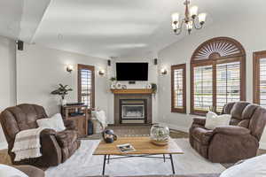 Carpeted living room with lofted ceiling, a premium fireplace, and a chandelier