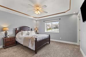 Bedroom featuring light colored carpet, a ceiling fan, a raised ceiling, and a textured ceiling