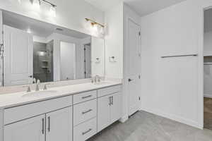 Bathroom with a shower stall, double vanity, a spacious closet, and light tile patterned flooring