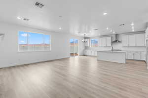 Unfurnished living room with light wood-type flooring, a chandelier, and recessed lighting