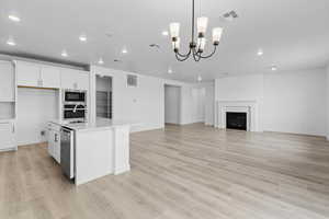 Kitchen with white cabinetry, a center island with sink, decorative light fixtures, light wood-style flooring, and recessed lighting