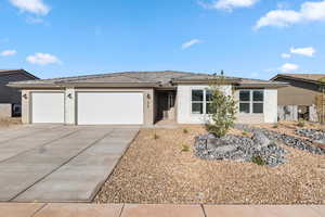 View of front facade featuring a garage, concrete driveway, and stucco siding