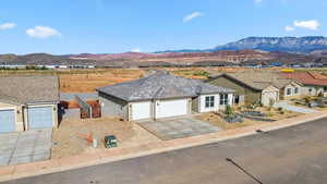 Single story home with a garage, a mountain view, driveway, and stucco siding