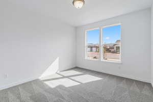 Empty room with light colored carpet and baseboards