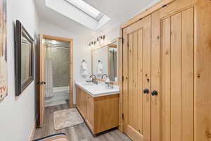 Bathroom with a skylight, vanity, shower / tub combo