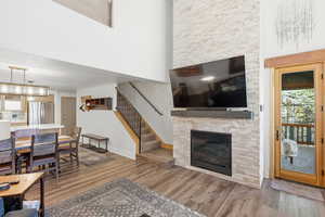 Living area featuring a high ceiling, light wood-style flooring, a fireplace with floor to ceiling fireplace surround.