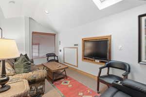 Living area featuring carpet flooring, vaulted ceiling, a skylight, and recessed lighting