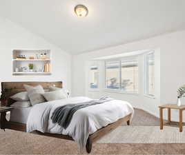 Carpeted bedroom with vaulted ceiling and baseboards