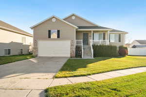 View of front of home with covered porch, a front yard, driveway, and an attached garage