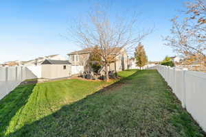 Fenced backyard featuring an outbuilding