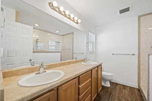Full bath featuring dark wood finished floors, double vanity, and walk in shower