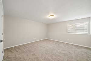 Empty room with light colored carpet and a textured ceiling