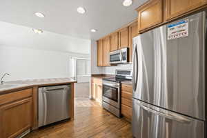 Kitchen with appliances with stainless steel finishes, recessed lighting, dark wood-style floors, and brown cabinets